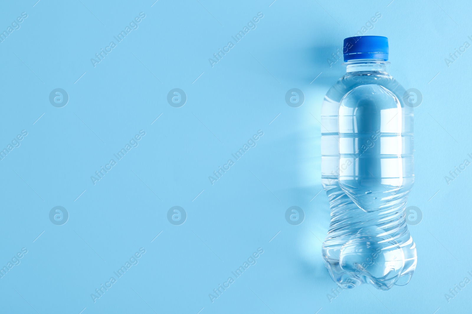 Photo of Bottle of water on color background, top view. Space for text