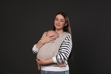 Photo of Mother holding her child in baby carrier on black background