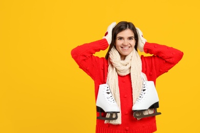 Photo of Happy woman with ice skates on yellow background. Space for text