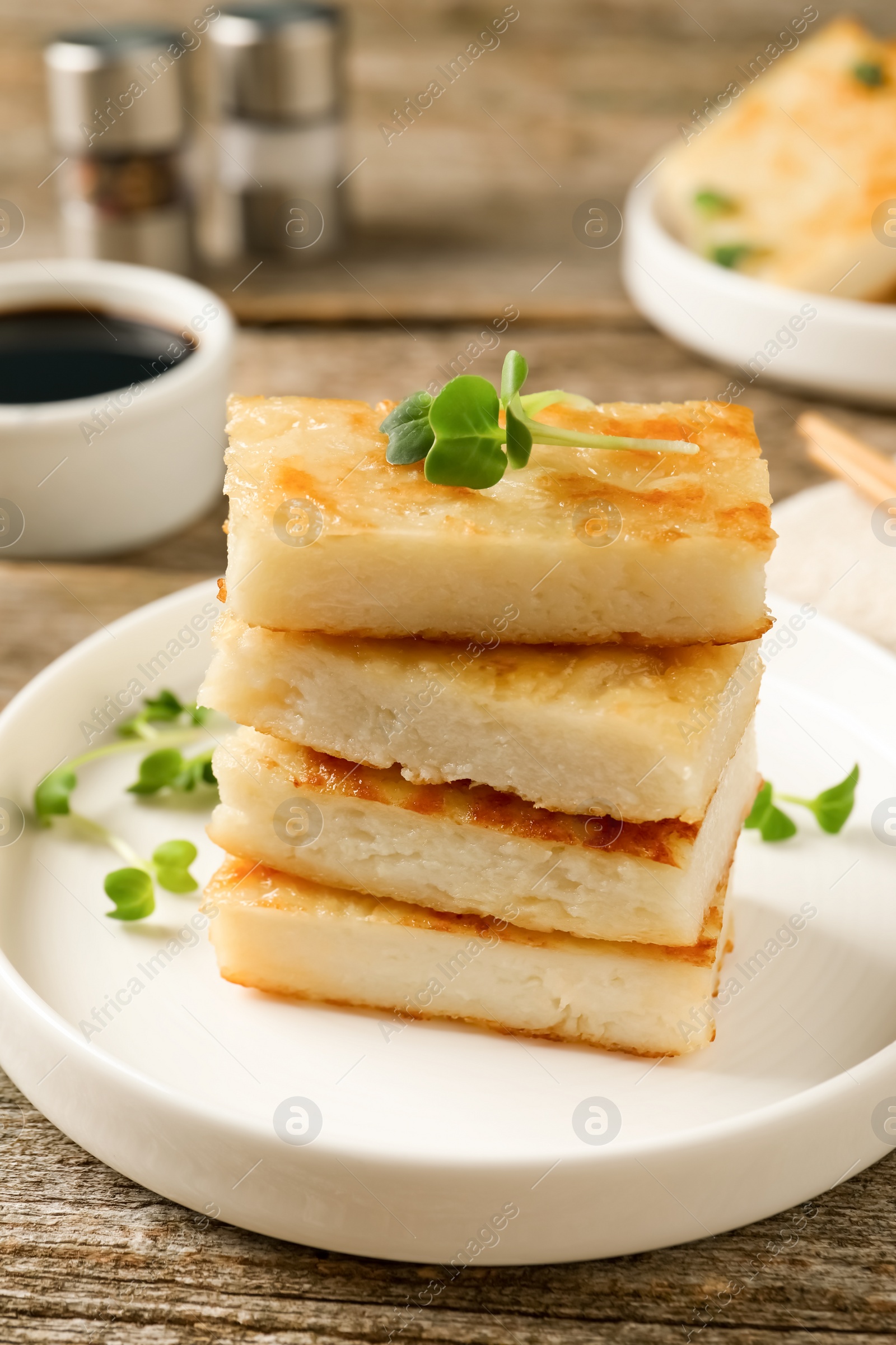 Photo of Delicious turnip cake with microgreens served on wooden table