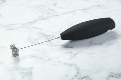 Black milk frother wand on white marble table