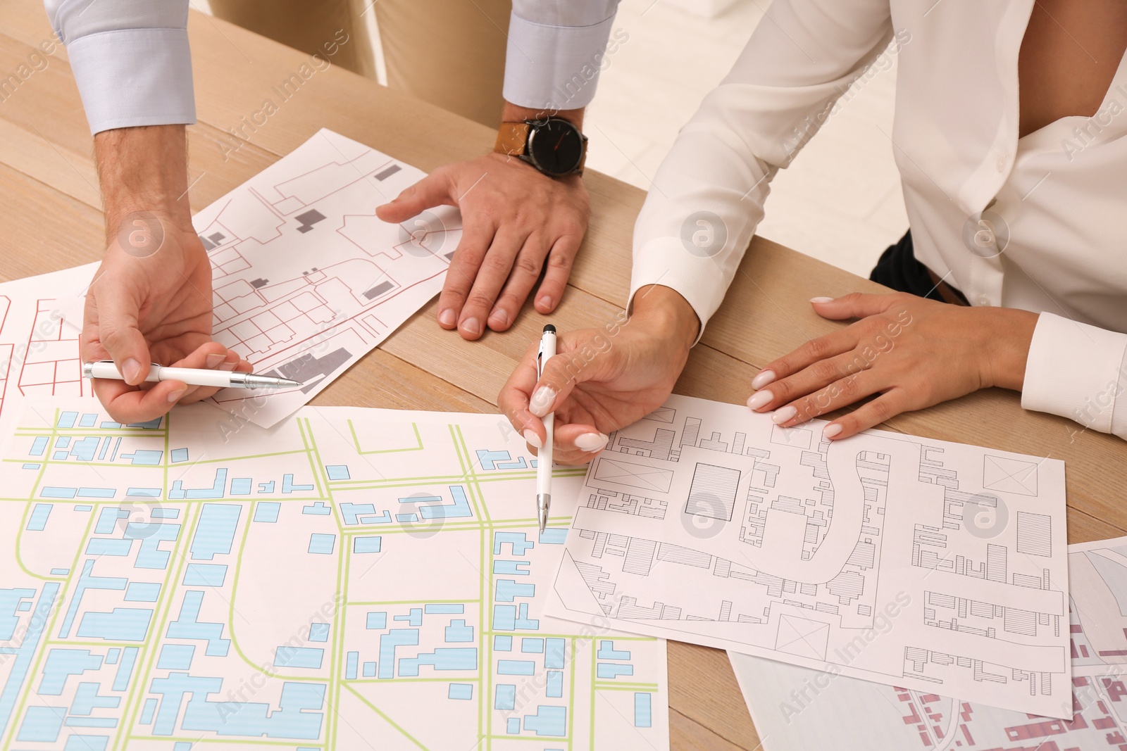 Photo of Professional cartographers working with cadastral map at table, closeup