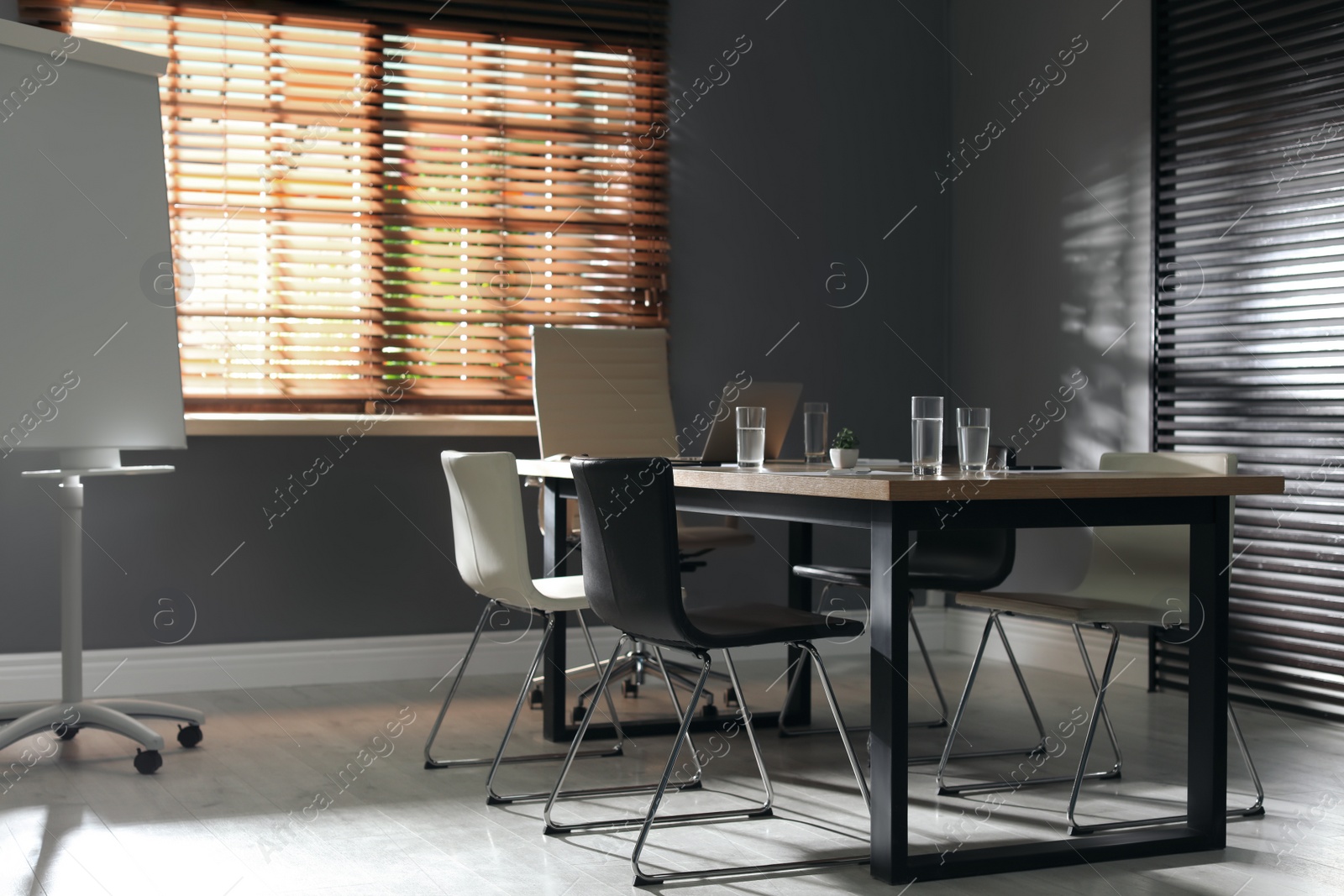 Photo of Stylish office interior with wooden table and flipchart