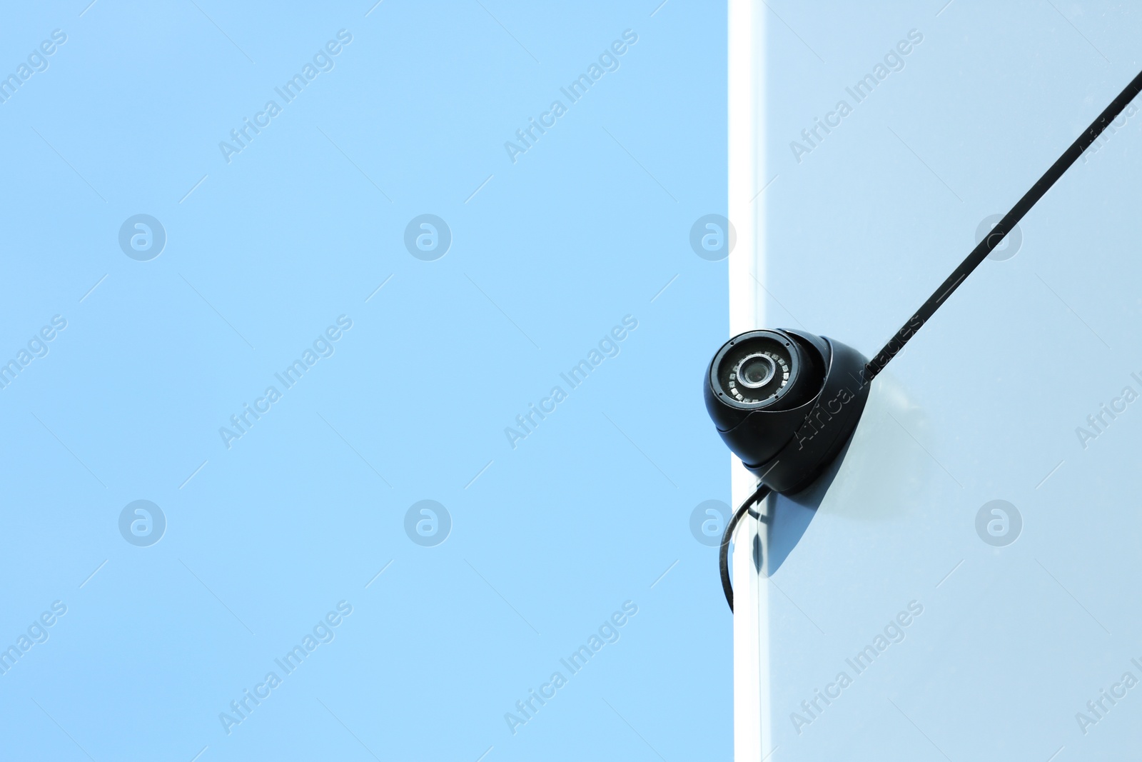 Photo of Modern CCTV security camera on building wall outdoors. Space for text