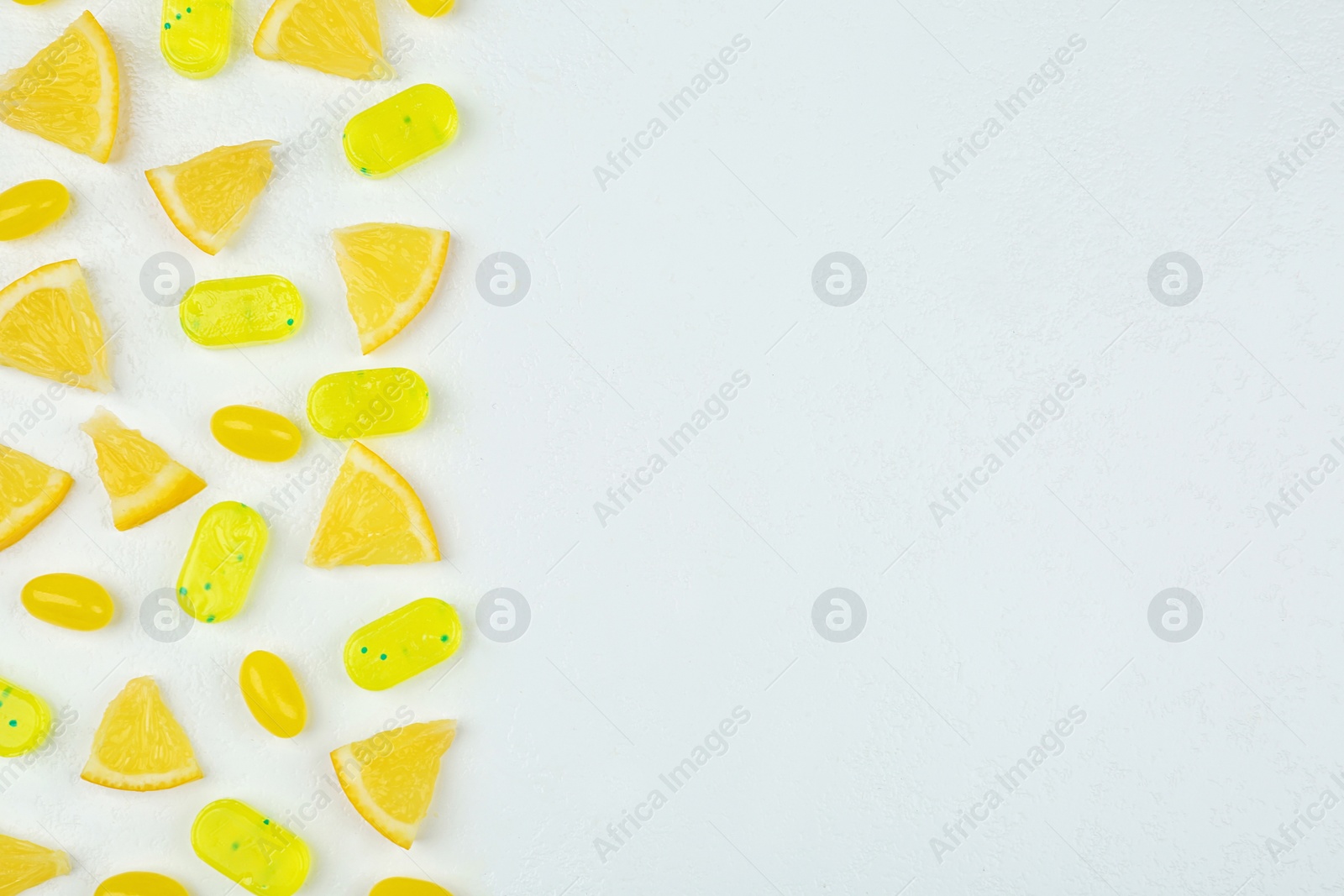 Photo of Fresh lemon slices and tasty candies on white table, flat lay. Space for text