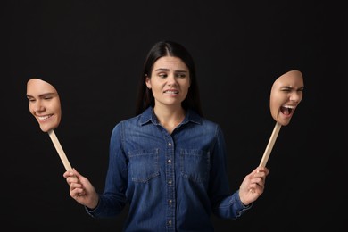 Image of Woman holding masks with her face showing different emotions on black background. Balanced personality