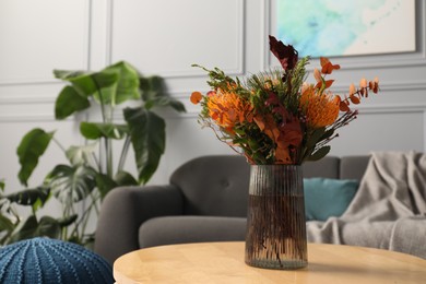 Photo of Vase with bouquet of beautiful leucospermum flowers on wooden coffee table, space for text