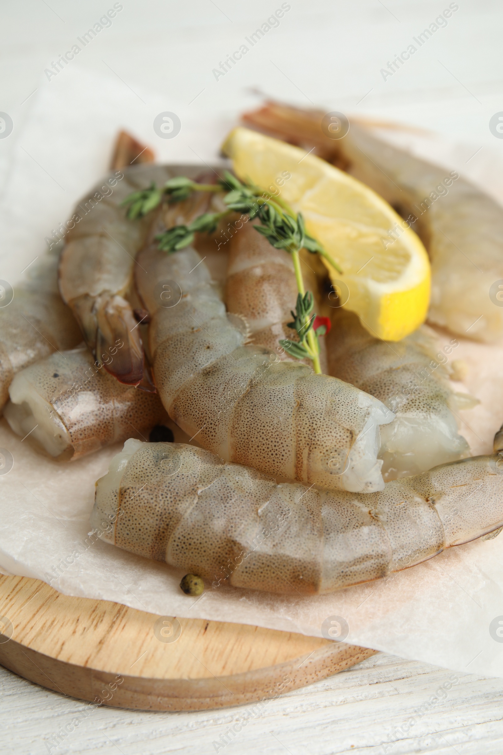 Photo of Fresh raw shrimps with lemon and thyme on white wooden table, closeup