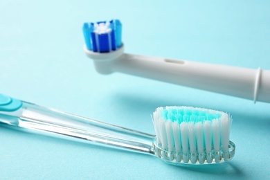 Manual and electric toothbrushes on color background, close up. Dental care