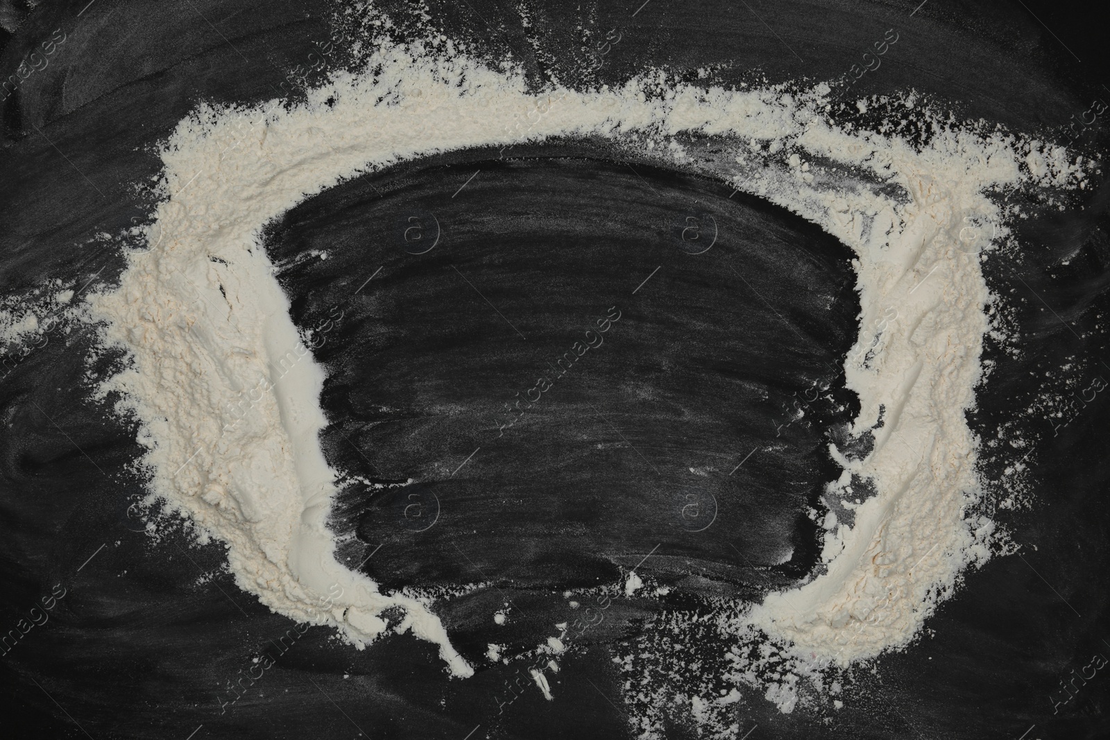 Photo of Frame made with flour on black table, top view. Space for text