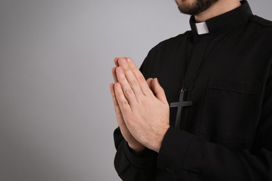 Photo of Priest praying on grey background, closeup. Space for text