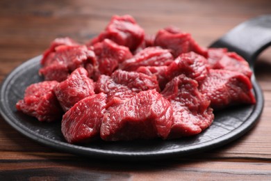 Pieces of raw beef meat on wooden table, closeup