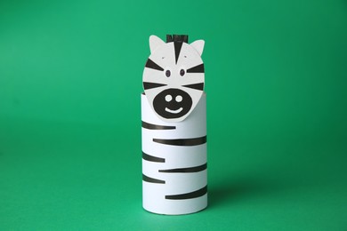 Photo of Toy zebra made from toilet paper hub on green background. Children's handmade ideas