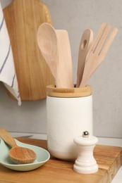 Set of different kitchen utensils on table near gray wall