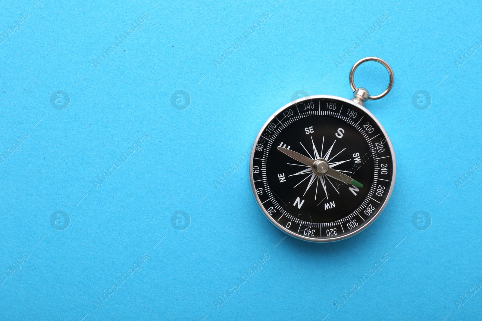 Photo of One compass on light blue background, top view. Space for text