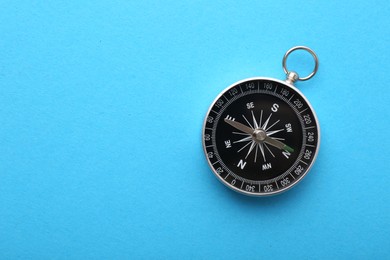 One compass on light blue background, top view. Space for text