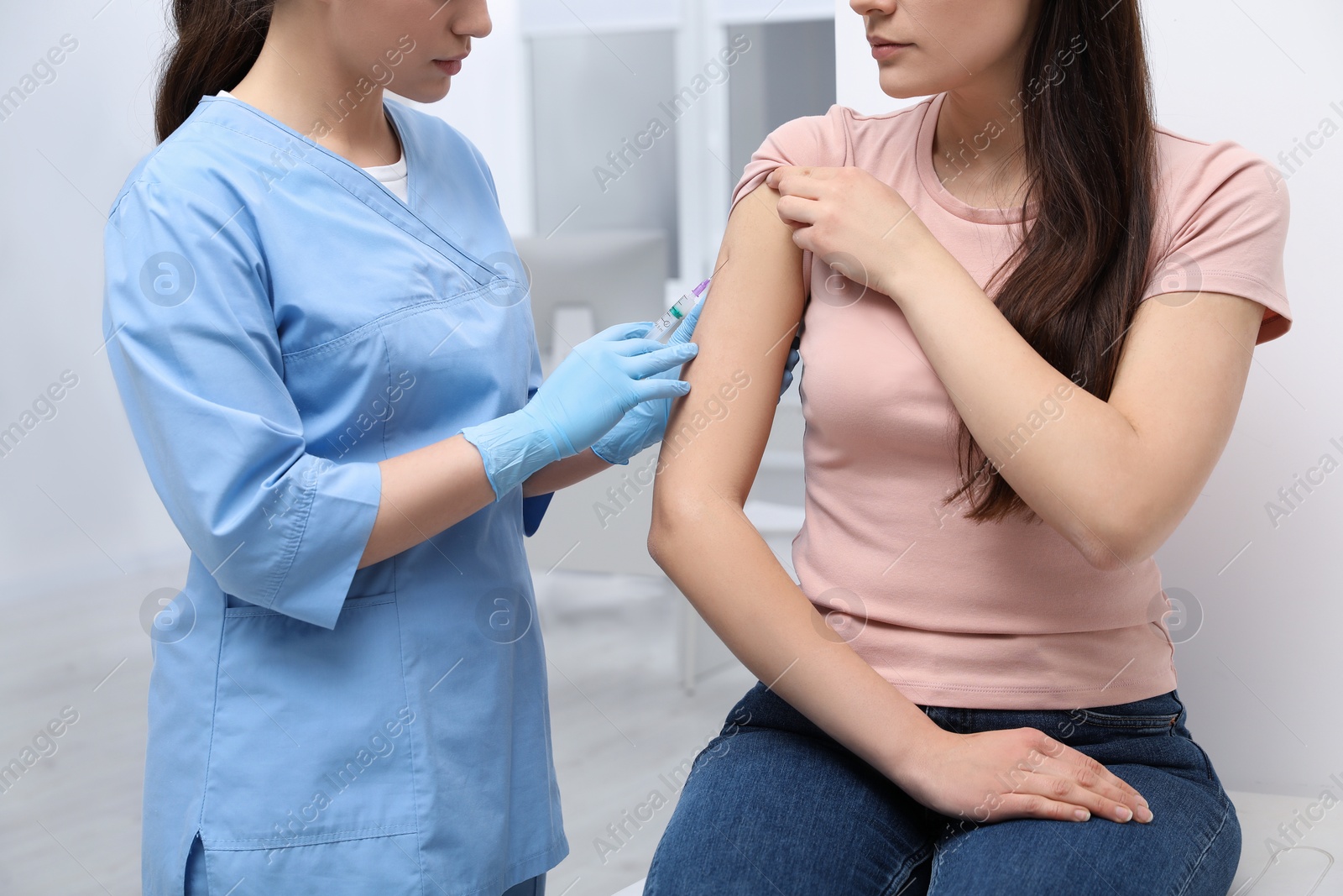 Photo of Doctor giving hepatitis vaccine to patient in clinic, closeup