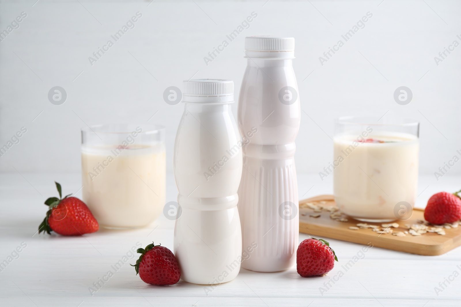 Photo of Tasty yogurt, oats and strawberries on white wooden table