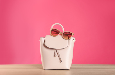 Photo of Stylish woman's bag and sunglasses on wooden table