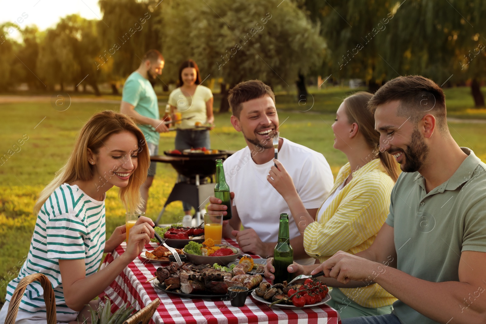 Photo of Happy friends with drinks and food at barbecue party in park