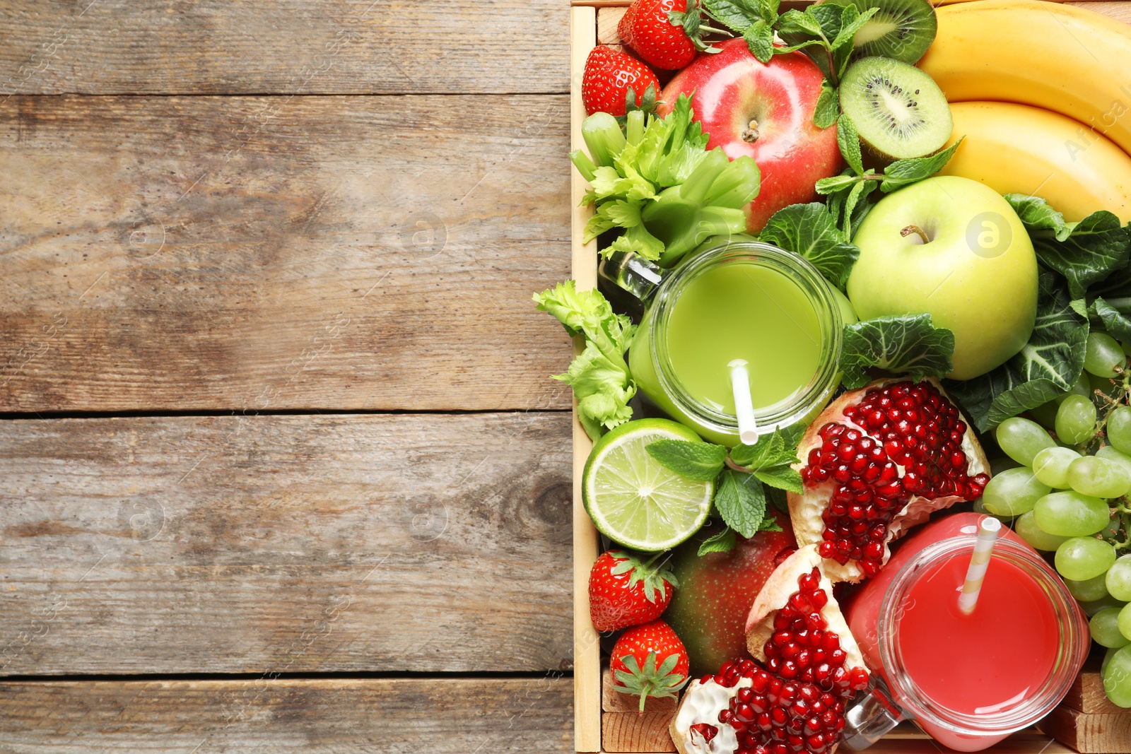 Photo of Wooden crate with juices in mason jars and fresh fruits on wooden background, top view. Space for text