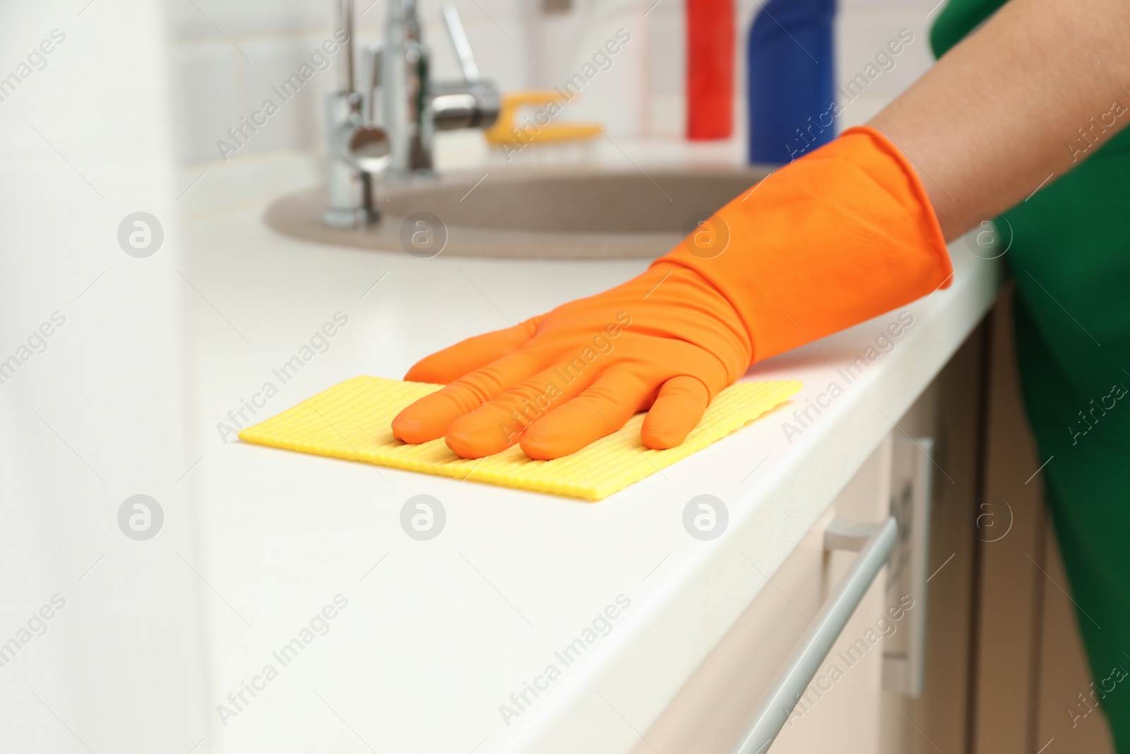Photo of Woman cleaning kitchen countertop with rag, closeup