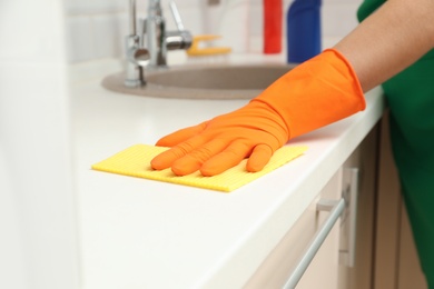 Woman cleaning kitchen countertop with rag, closeup