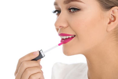 Photo of Beautiful woman applying liquid lipstick on light background