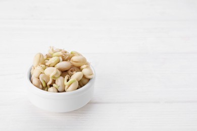 Photo of Sprouted kidney beans in bowl on white wooden table, closeup. Space for text