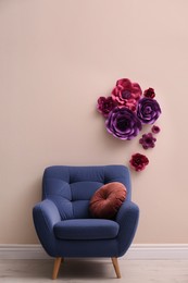 Photo of Comfortable armchair near wall with floral decor in room. Interior design