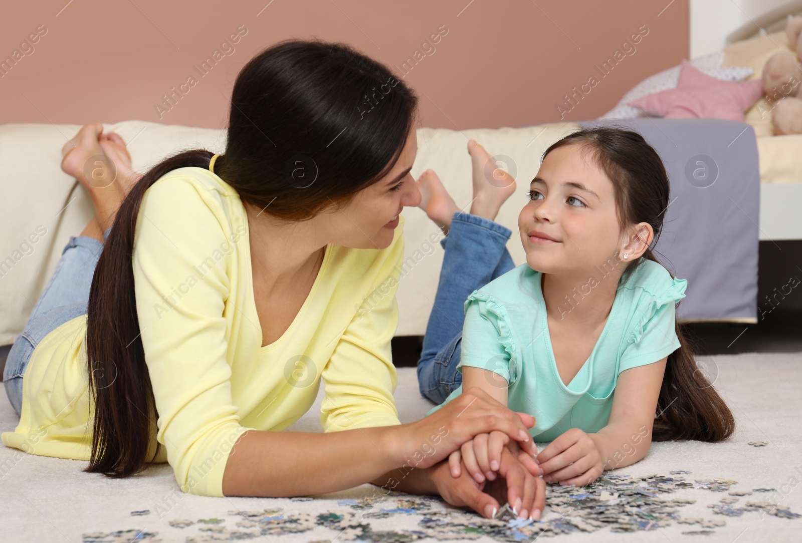 Photo of Happy mother and daughter doing jigsaw puzzle together in bedroom. Single parenting