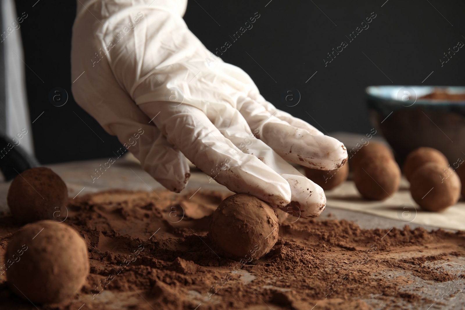 Photo of Woman preparing tasty chocolate truffles at table, closeup