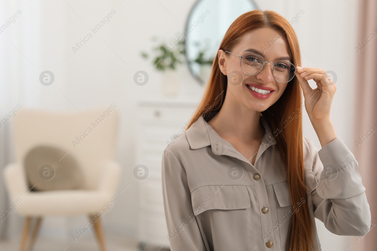 Photo of Portrait of beautiful young woman with red hair at home. Attractive lady smiling and looking into camera. Space for text