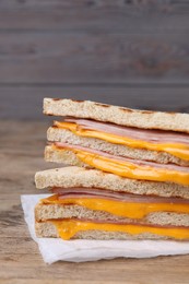 Photo of Delicious grilled sandwiches with ham and cheese on wooden table, closeup