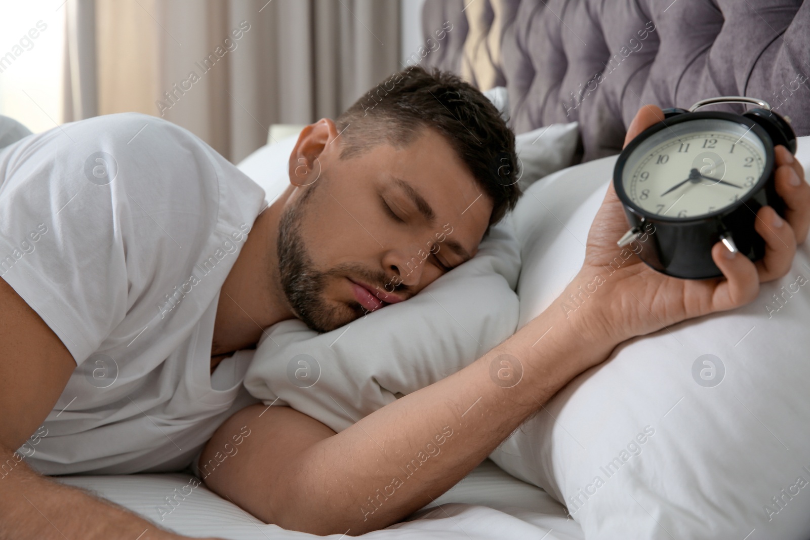 Photo of Man with alarm clock sleeping at home in morning