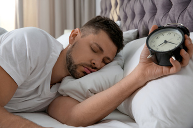 Photo of Man with alarm clock sleeping at home in morning