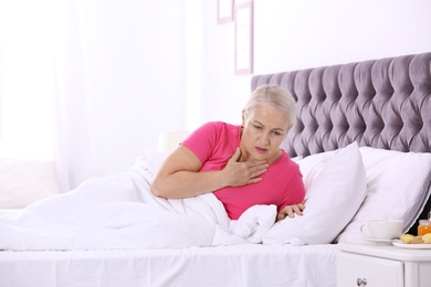 Photo of Ill mature woman suffering from cough in bed