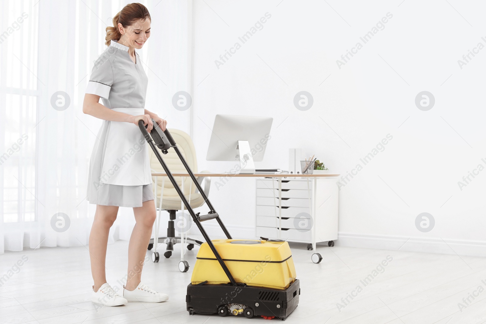 Photo of Female worker with floor cleaning machine indoors