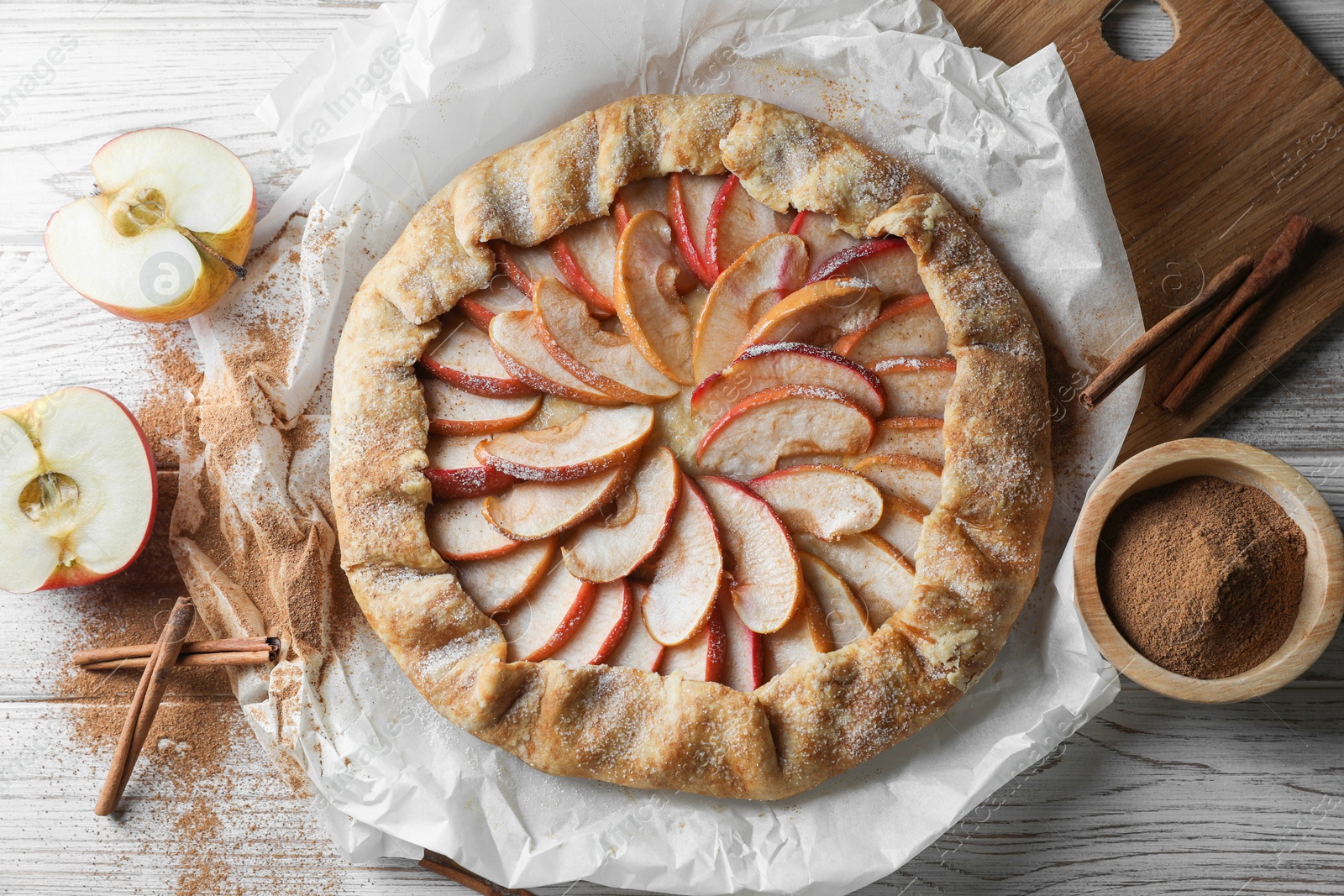 Photo of Delicious apple galette and cinnamon on white wooden table, flat lay