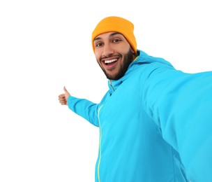 Photo of Smiling young man taking selfie and showing thumbs up on white background