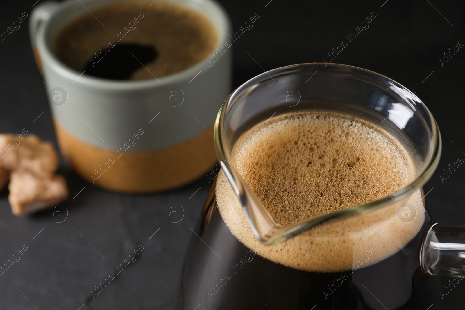 Photo of Turkish coffee in cezve and cup on dark grey table, closeup