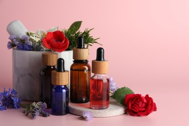 Photo of Aromatherapy. Different essential oils, flowers, mortar and pestle on pink background