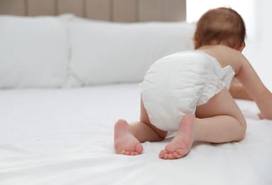 Cute little baby in diaper on bed, closeup. Space for text