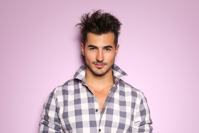 Young man with trendy hairstyle posing on color background