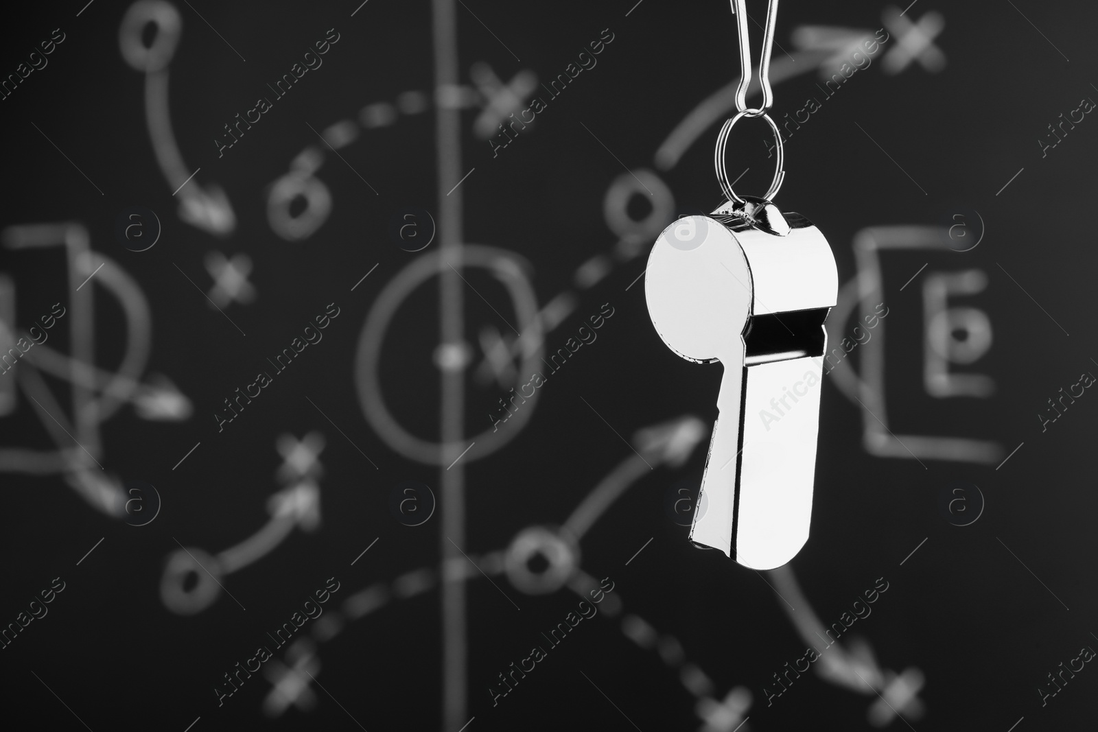 Photo of Referee whistle against chalkboard with game scheme, closeup. Space for text