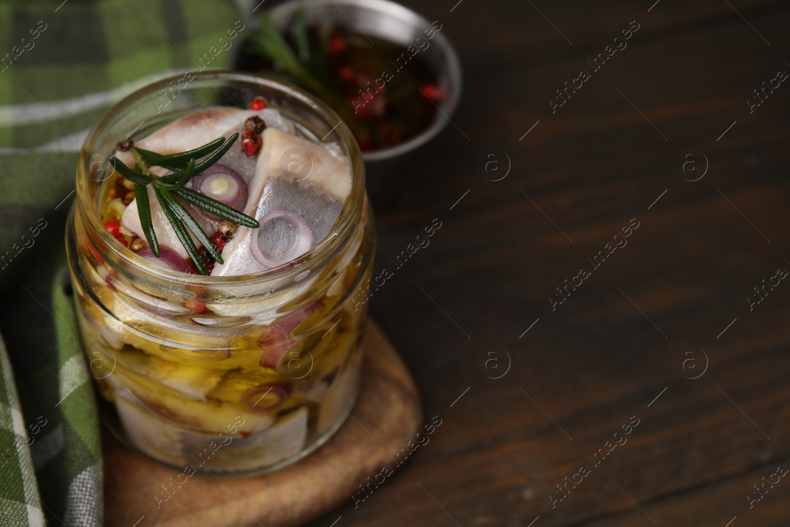 Photo of Tasty marinated fish with onion and rosemary in jar on wooden table, closeup. Space for text