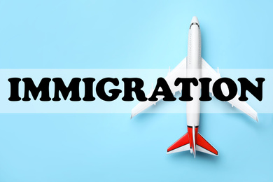 Toy plane on light blue background, top view. Immigration concept