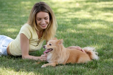 Photo of Young woman with her cute dog on green grass in park