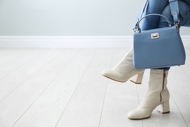 Woman wearing stylish leather shoes with bag indoors, closeup. Space for text