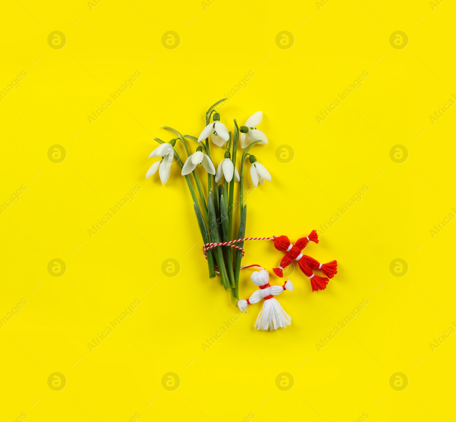 Photo of Beautiful snowdrops with traditional martisor on yellow background, flat lay. Symbol of first spring day